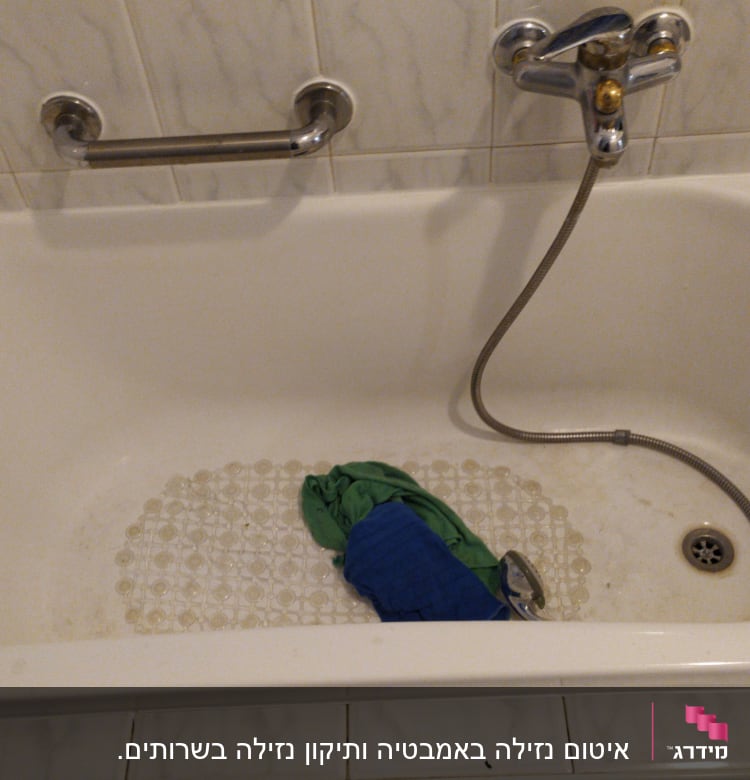 אמבטיה עם ברז, צינור ומגבת ירוקה